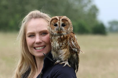 Woman with Fletcher the tawny owl perched on her shoulder